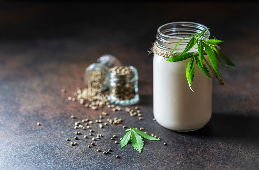 Sklenice konopného proteinu ozdobená konopným lístkem a semínky